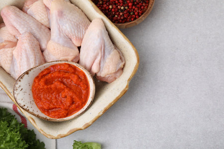 Flat lay composition with marinade, raw chicken and other products on light textured table. Space for textの写真素材