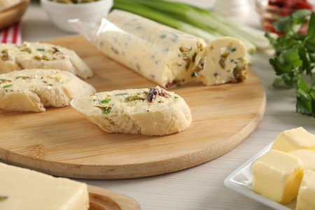 Tasty butter with olives, green onion, chili pepper and bread on wooden table