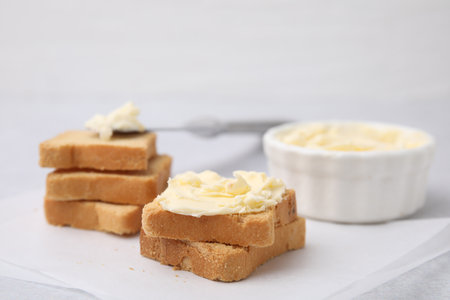 Slices of bread with tasty butter on light table, closeup