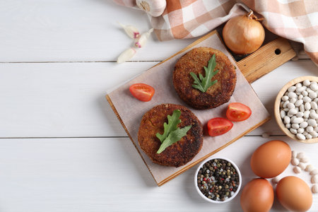 Vegetarian product. Tasty bean cutlets served on white wooden table, flat lay. Space for text