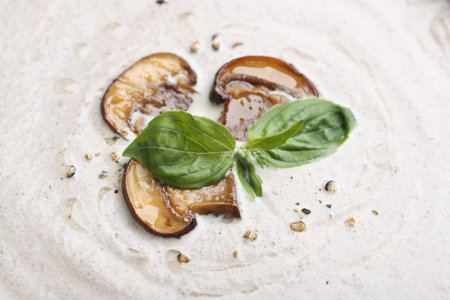Tasty homemade mushroom soup with fresh basil leaves as background, closeupの写真素材
