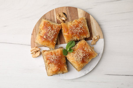 Eastern sweets. Pieces of tasty baklava on white wooden table, top view