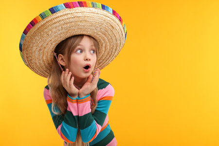 Emotional girl in Mexican sombrero hat on orange background. Space for textの写真素材