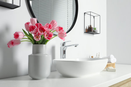 Vase with beautiful pink tulips near sink in bathroomの写真素材