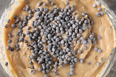 Raw dough with chocolate chips in bowl on table, top viewの写真素材