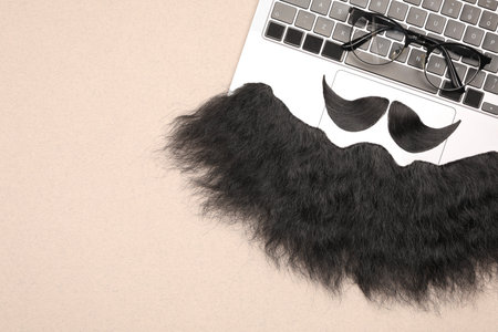 Flat lay composition with artificial moustache and glasses on light brown background, space for text