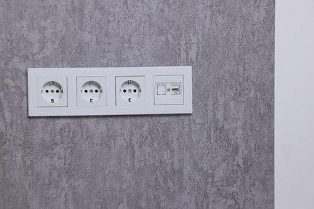 Electric power sockets on gray wall indoors, space for text
