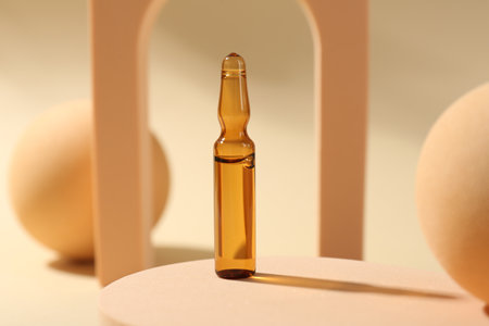 Stylish presentation of glass ampoule with liquid on beige backgroundの写真素材