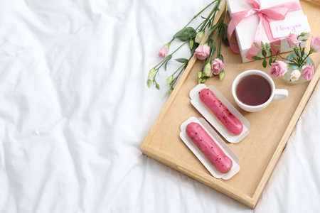 Tasty breakfast served in bed. Delicious eclairs, tea, gift box, flowers and card with the phrase I...