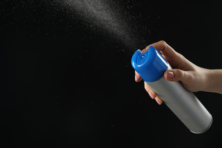 Woman spraying air freshener on black background, closeup. Space for textの写真素材