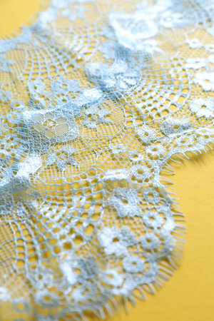 Light blue lace on yellow background, closeupの写真素材