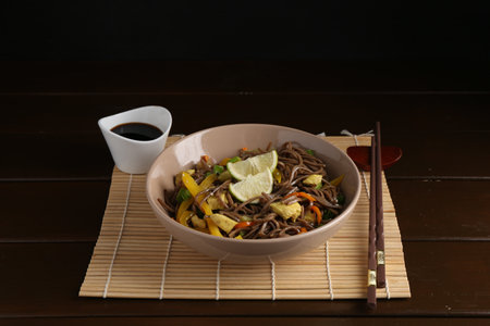 Stir-fry. Delicious cooked noodles with chicken and vegetables in bowl served on wooden tableの写真素材