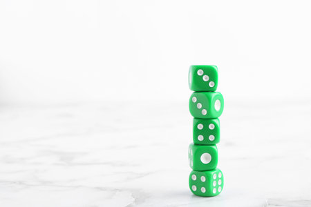 Many stacked green dices on white marble table. Space for textの写真素材