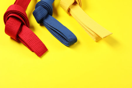 Colorful karate belts on yellow background, space for textの写真素材