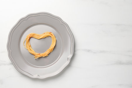 Heart made with spaghetti on white table, top view. Space for textの写真素材