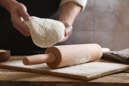 Man making dough at wooden table, closeup