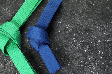 Karate belts on gray background, flat lay. Space for text