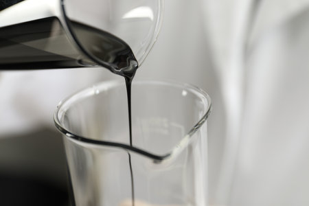 Pouring crude oil into beaker against blurred background, closeupの写真素材