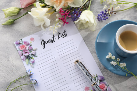 Guest list, coffee, pen and beautiful flowers on light textured table. Space for text