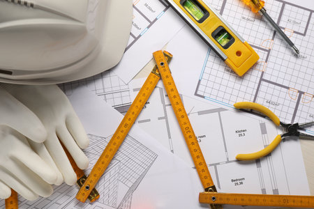 Flat lay composition with building level and other construction tools on white wooden table
