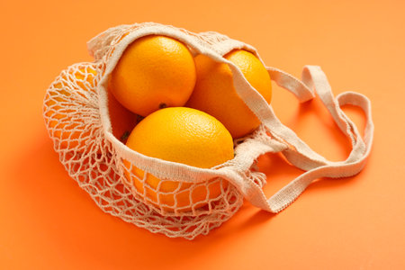 String bag with fresh oranges on color backgroundの写真素材