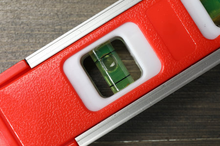 Red building level on wooden table, top view