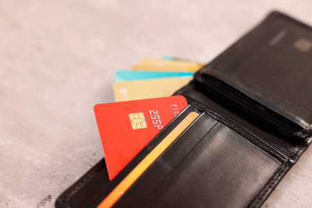 Many different credit cards and leather wallet on gray table, closeup