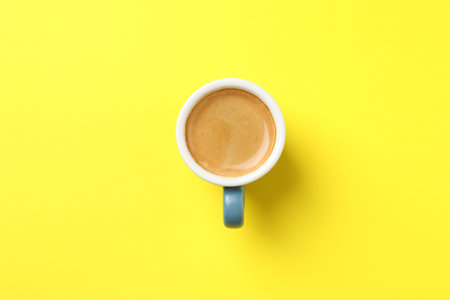 Aromatic coffee in cup on yellow background, top viewの写真素材
