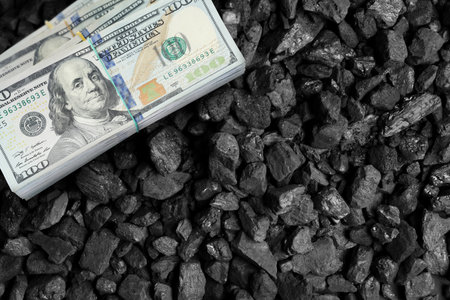 Dollar banknotes on pieces of coal, top view. Resource price