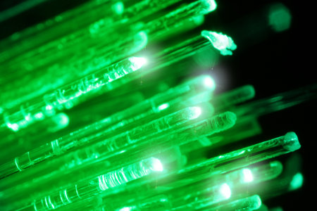 Optical fiber strands transmitting green light on black background, macro view