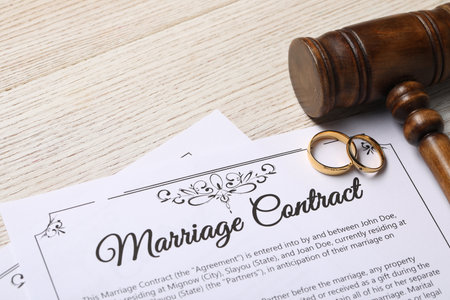 Marriage contract, golden wedding rings and gavel on wooden tableの写真素材
