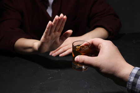 Alcohol addiction. Woman refusing glass of whiskey at dark table, closeupの写真素材