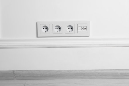 Electric power sockets on white wall indoors