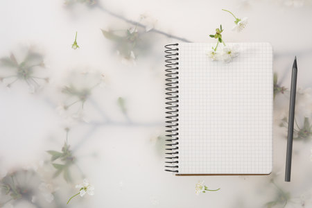 Guest list. Notebook, pencil and beautiful cherry tree blossoms on spring floral background, flat lay. Space for textの写真素材