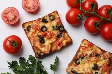 Tasty pizza toasts, fresh tomatoes and parsley on white tiled table, flat layの写真素材