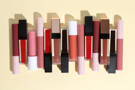 Different lip glosses on pale yellow background, flat layの写真素材