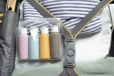 Plastic bag of cosmetic travel kit and clothes in suitcase, top viewの写真素材