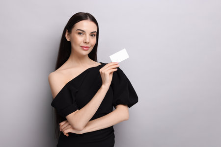 Woman holding blank business card on light grey background. Space for textの写真素材