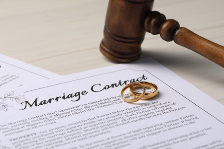 Marriage contracts, gold rings and gavel on light wooden table, closeupの写真素材