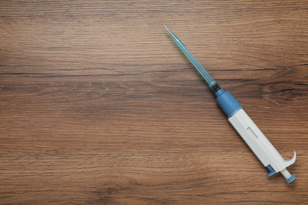 Laboratory analysis. Micropipette with liquid on wooden table, top view. Space for textの写真素材