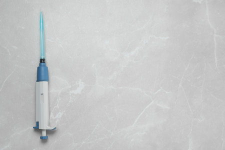 Laboratory analysis. Micropipette with liquid on light gray marble table, top view. Space for textの写真素材