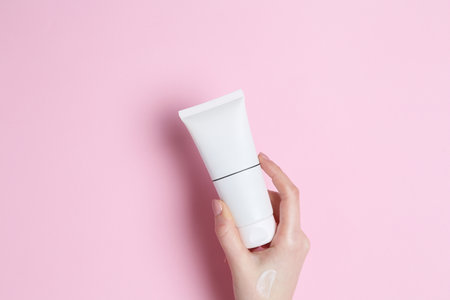 Woman holding tube of cream on pink background, closeupの写真素材