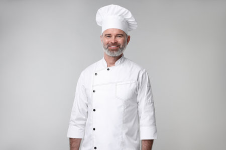 Happy chef in uniform on grey backgroundの写真素材