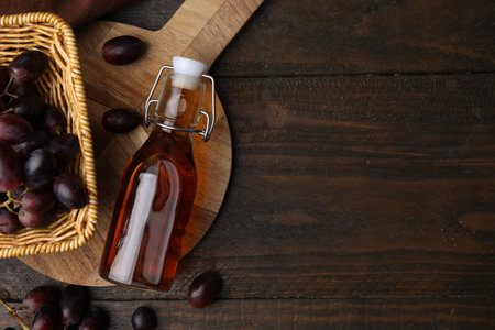 Bottle with wine vinegar and grapes on wooden table, flat lay. Space for textの写真素材