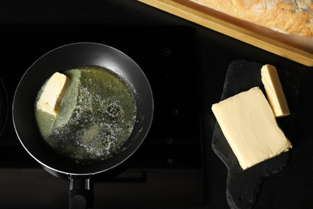 Melting butter in frying pan and dairy product on black table, top viewの写真素材