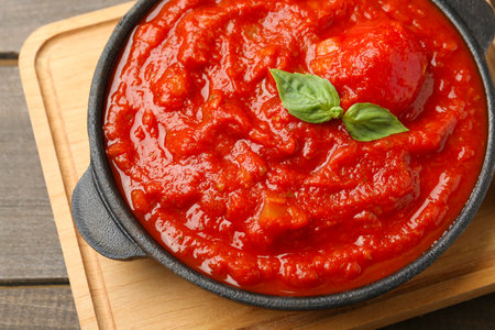 Homemade tomato sauce and basil in bowl on wooden tableの写真素材