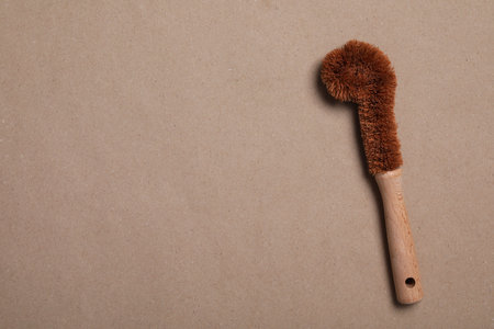 Cleaning brush on pale brown background, top view. Space for text