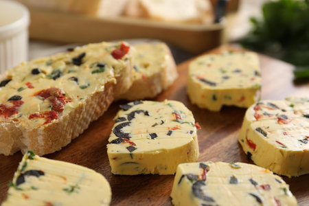Tasty butter with olives, chili pepper, parsley and bread on table, closeupの写真素材
