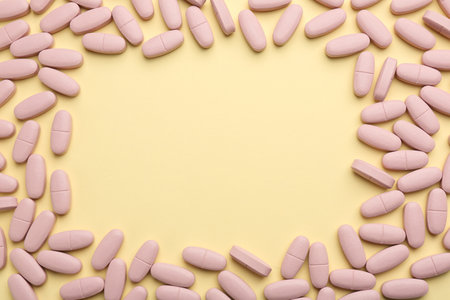 Frame made of vitamin pills on pale yellow background, top view. Space for textの写真素材