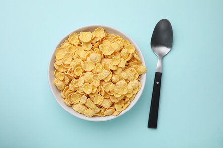Breakfast cereal. Tasty corn flakes in bowl on light blue table, flat layの写真素材